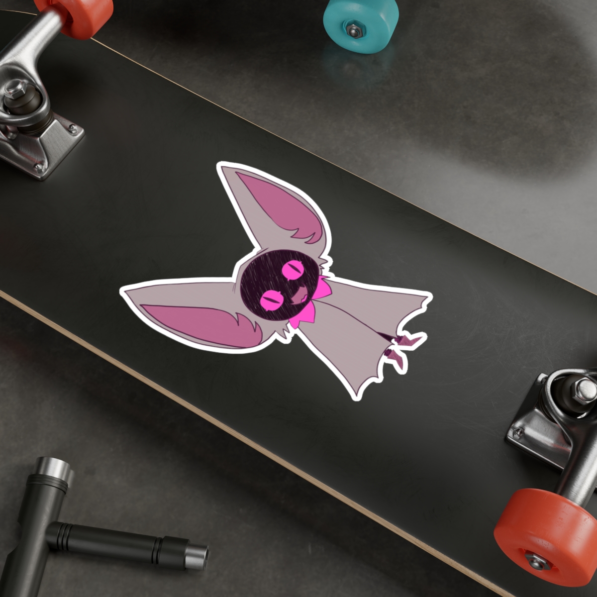 Small purple bat sticker with big expressive eyes on a skateboard